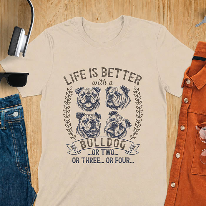 Sand unisex t-shirt with distressed vintage graphic featuring four Bulldog portrait illustrations in a two-by-two grid framed by laurel branches, text reads Life Is Better with a Bulldog or two or three or four