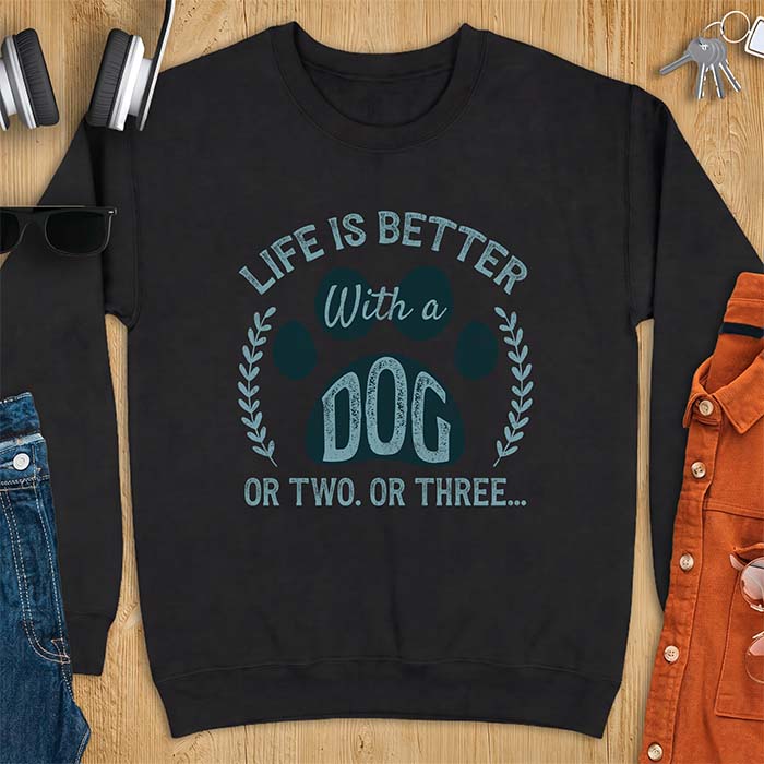 Black sweatshirt with a graphic of a large paw print framed by a laurel wreath on either side and the text Life Is Better With a Dog Or Two Or Three