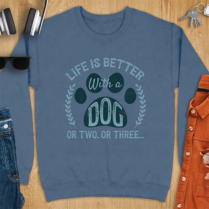 Indigo Blue sweatshirt with a graphic of a large paw print framed by a laurel wreath on either side and the text Life Is Better With a Dog Or Two Or Three