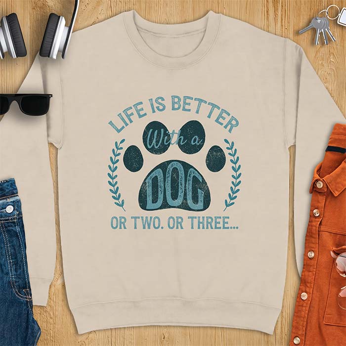 Sand sweatshirt with a graphic of a large paw print framed by a laurel wreath on either side and the text Life Is Better With a Dog Or Two Or Three