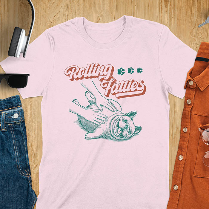 Light pink t-shirt with Rolling Fatties script text and French Bulldog being petted by human hands in line drawing style.