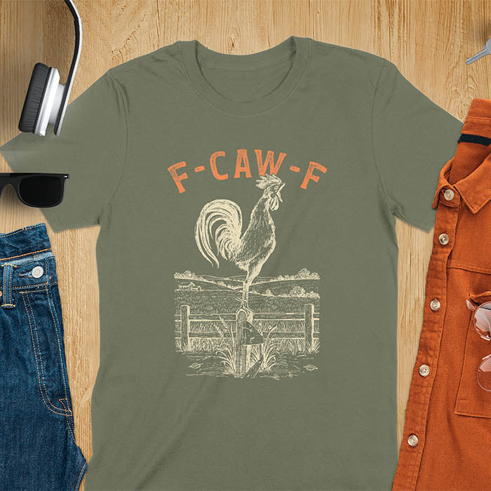 Military Green t-shirt with F-CAW-F text and detailed rooster illustration standing on wooden fence in vintage farm scene style
