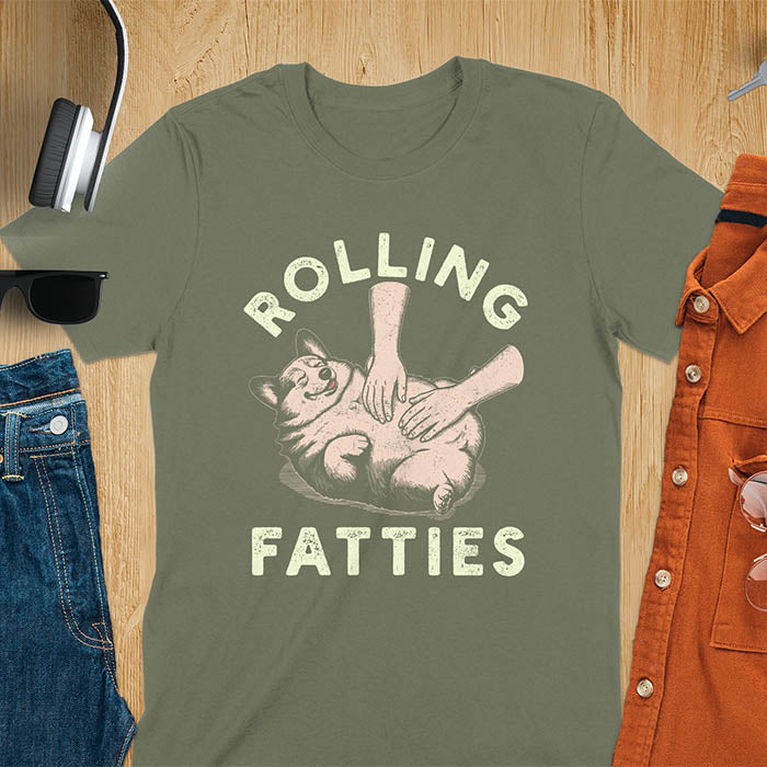 Chubby corgi illustration enjoying tummy rubs with Rolling Fatties text in textured lettering on military green tee