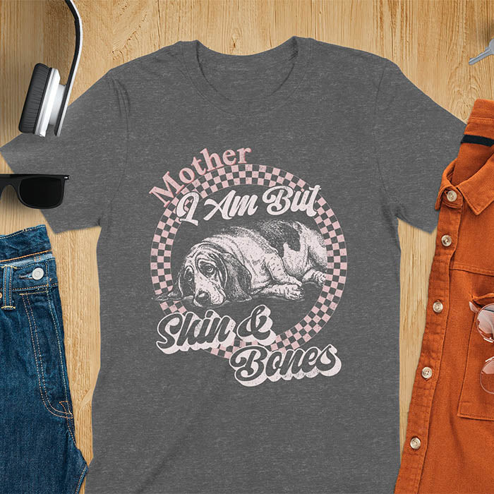 Dark heather t-shirt with a vintage graphic of a basset hound lying down inside a retro checkered circle, with the text Mother I Am But Skin and Bones