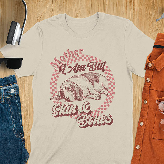 Sand t-shirt with a vintage graphic of a basset hound lying down inside a retro checkered circle, with the text Mother I Am But Skin and Bones