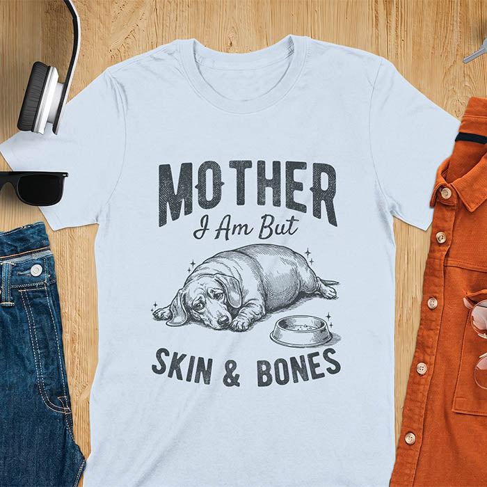 Light blue graphic tee with vintage sketch of a chonky sausage dog lying next to an empty bowl, text reads Mother I Am But Skin And Bones