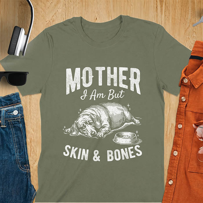 Military green graphic tee with vintage sketch of a chonky sausage dog lying next to an empty bowl, text reads Mother I Am But Skin And Bones