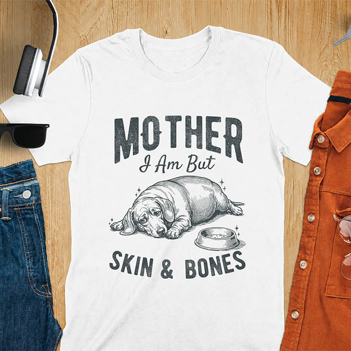 White graphic tee with vintage sketch of a chonky sausage dog lying next to an empty bowl, text reads Mother I Am But Skin And Bones