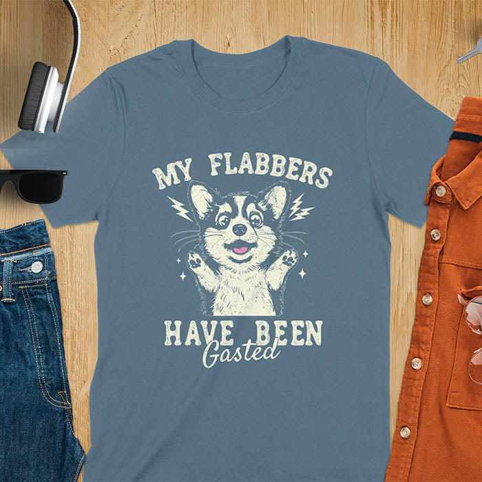 A indigo blue t-shirt with a bewildered corgi with its paws up. Text: MY FLABBERS above and HAVE BEEN GASTED below. This sarcastic tee-shirt features kawaiiness cuteness, a genz meme tee. A depress meme and anxiety tshirt, a funny gag gift. One of those shirts that go hard, a weirdcore memes and sad core aesthetic. A mom gift alternative.