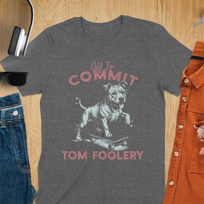Dark heather blue t-shirt featuring a pitbull riding a skateboard with text Off To Commit Tom Foolery in vintage red lettering