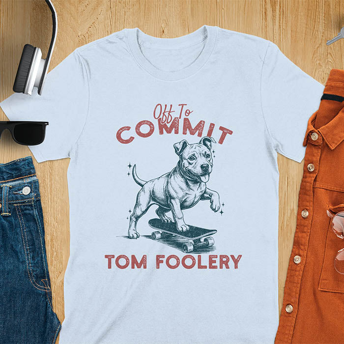 Light blue t-shirt featuring a pitbull riding a skateboard with text Off To Commit Tom Foolery in vintage red lettering