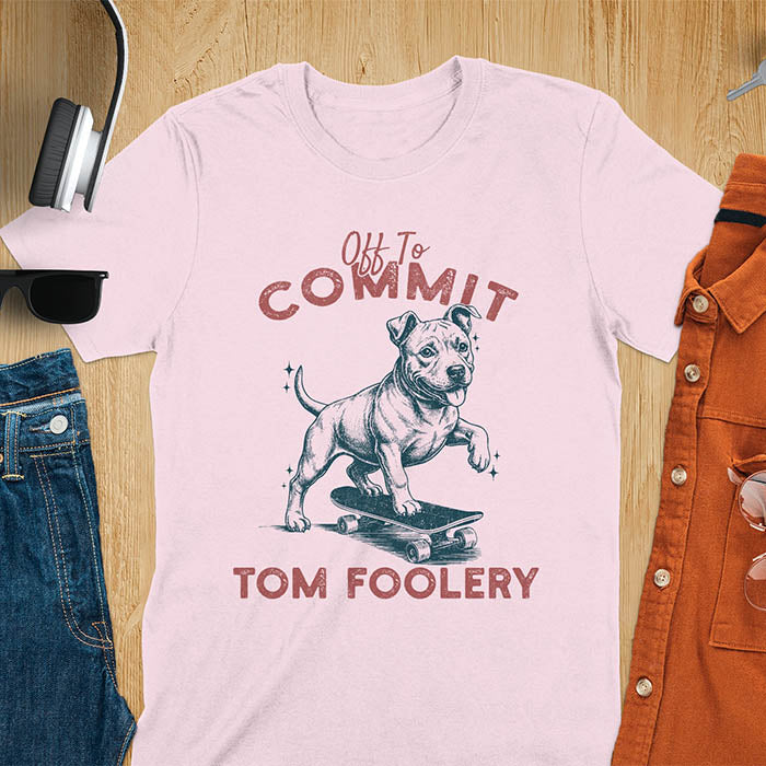 Light pink t-shirt featuring a pitbull riding a skateboard with text Off To Commit Tom Foolery in vintage red lettering