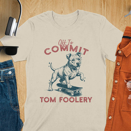 Sand color t-shirt featuring a pitbull riding a skateboard with text Off To Commit Tom Foolery in vintage red lettering