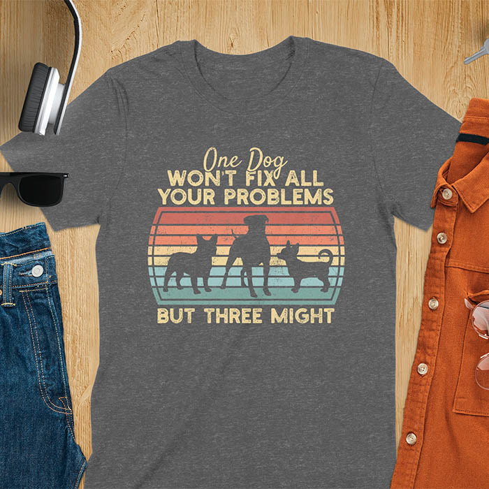 Dark heather t-shirt with text 'One dog won't fix all your problems but three might' and three dog silhouettes on vintage sunset stripes