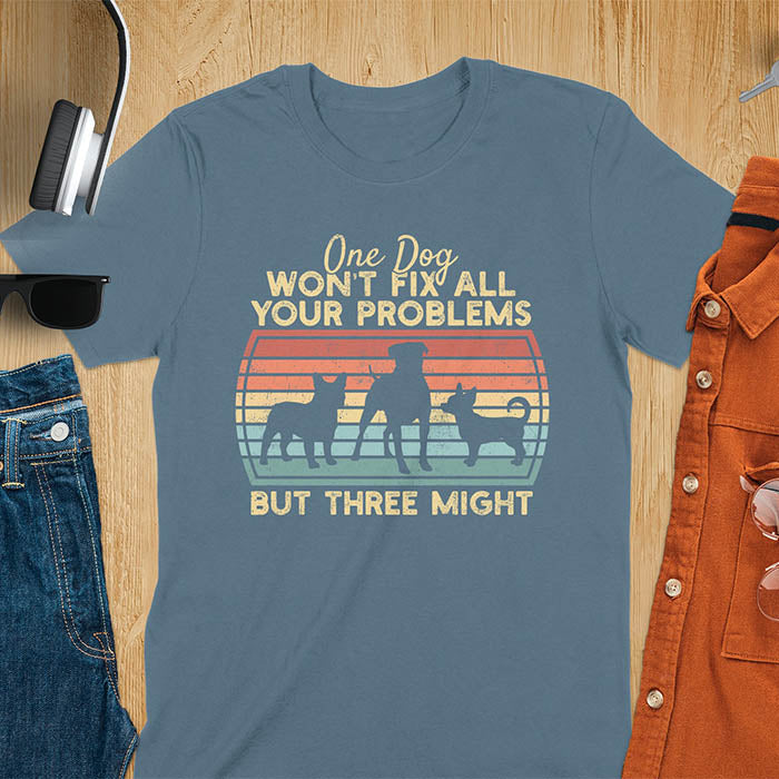 Indigo blue t-shirt with text 'One dog won't fix all your problems but three might' and three dog silhouettes on vintage sunset stripes