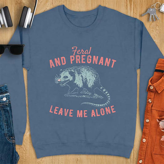 Indigo Blue sweatshirt with a graphic of a hissing opossum baring its teeth with a striped tail, plus the text Feral And Pregnant Leave Me Alone.