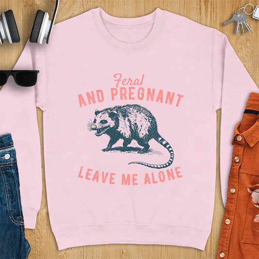 Light Pink sweatshirt with a graphic of a hissing opossum baring its teeth with a striped tail, plus the text Feral And Pregnant Leave Me Alone.