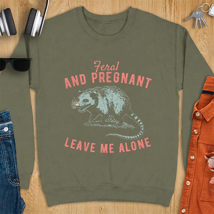Military Green sweatshirt with a graphic of a hissing opossum baring its teeth with a striped tail, plus the text Feral And Pregnant Leave Me Alone.