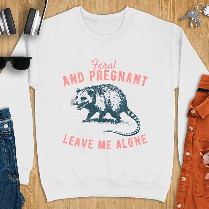 White sweatshirt with a graphic of a hissing opossum baring its teeth with a striped tail, plus the text Feral And Pregnant Leave Me Alone.