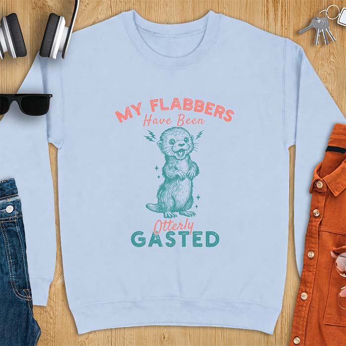 Light Blue sweatshirt with a graphic of a startled otter standing upright with paws clasped and mouth open in shock with lightning bolts on either side, featuring the text My Flabbers Have Been Otterly Gasted.