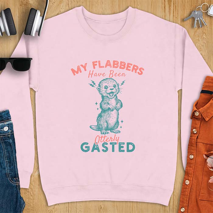 Light Pink sweatshirt with a graphic of a startled otter standing upright with paws clasped and mouth open in shock with lightning bolts on either side, featuring the text My Flabbers Have Been Otterly Gasted.
