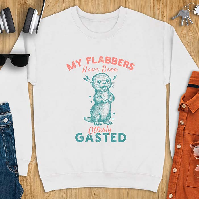 White sweatshirt with a graphic of a startled otter standing upright with paws clasped and mouth open in shock with lightning bolts on either side, featuring the text My Flabbers Have Been Otterly Gasted.