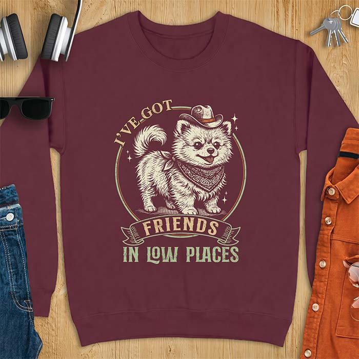Maroon sweatshirt with a vintage western illustration of a fluffy Pomeranian wearing a cowboy hat and a paisley bandana, with the text I've Got arched above it and Friends In Low Places below it