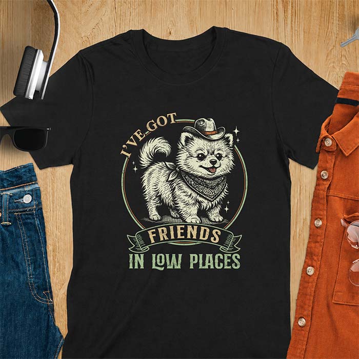 Black t-shirt with a vintage western illustration of a fluffy Pomeranian wearing a cowboy hat and a paisley bandana, with the text I've Got arched above it and Friends In Low Places below it