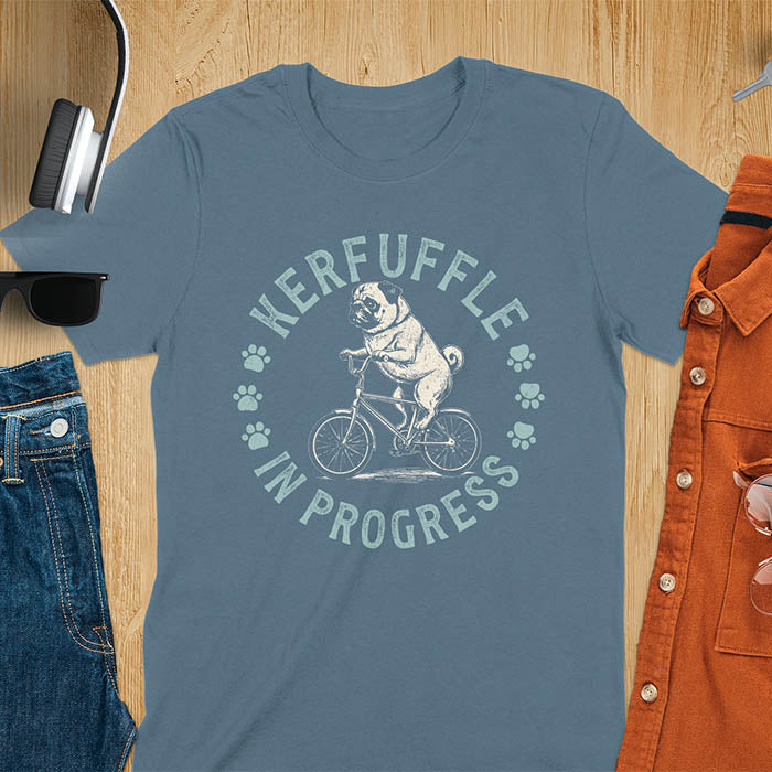 Pug on bicycle sketch-style graphic with Kerfuffle In Progress text and paw prints on indigo blue t-shirt