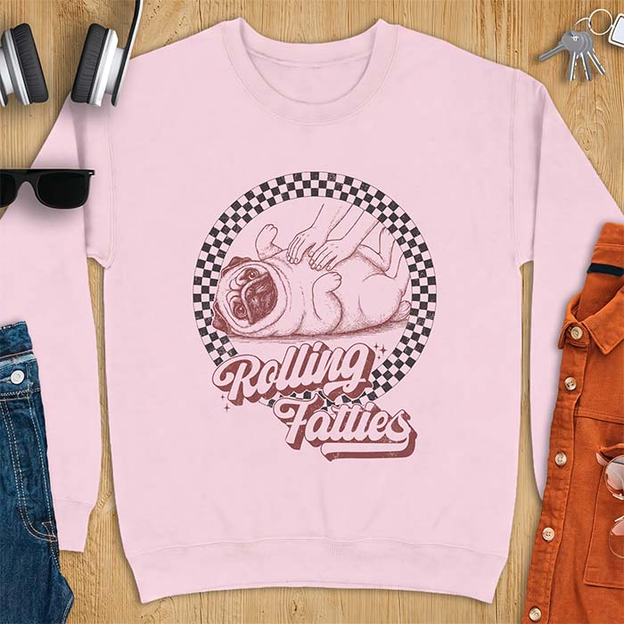 Light Pink sweatshirt with a graphic of a pug lying on its back inside a checkered circle while a pair of hands press into its rolled folds and the text Rolling Fatties