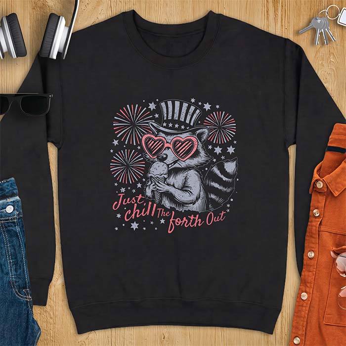 Black sweatshirt with a graphic of a raccoon in a striped top hat and heart-shaped sunglasses eating an ice cream cone in front of fireworks and stars, printed with the text Just Chill The Forth Out