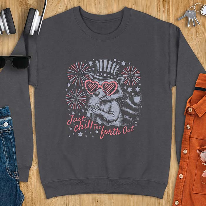 Dark Heather sweatshirt with a graphic of a raccoon in a striped top hat and heart-shaped sunglasses eating an ice cream cone in front of fireworks and stars, printed with the text Just Chill The Forth Out