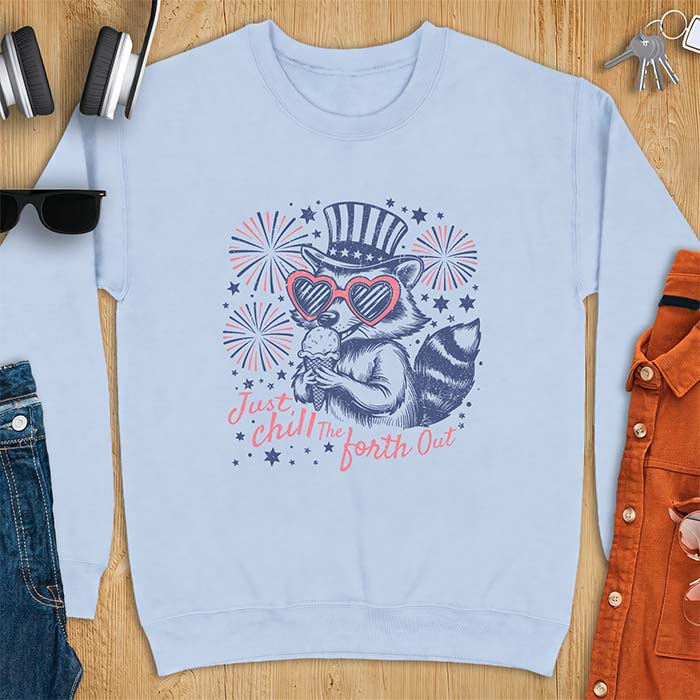 Light Blue sweatshirt with a graphic of a raccoon in a striped top hat and heart-shaped sunglasses eating an ice cream cone in front of fireworks and stars, printed with the text Just Chill The Forth Out