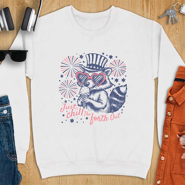 White sweatshirt with a graphic of a raccoon in a striped top hat and heart-shaped sunglasses eating an ice cream cone in front of fireworks and stars, printed with the text Just Chill The Forth Out