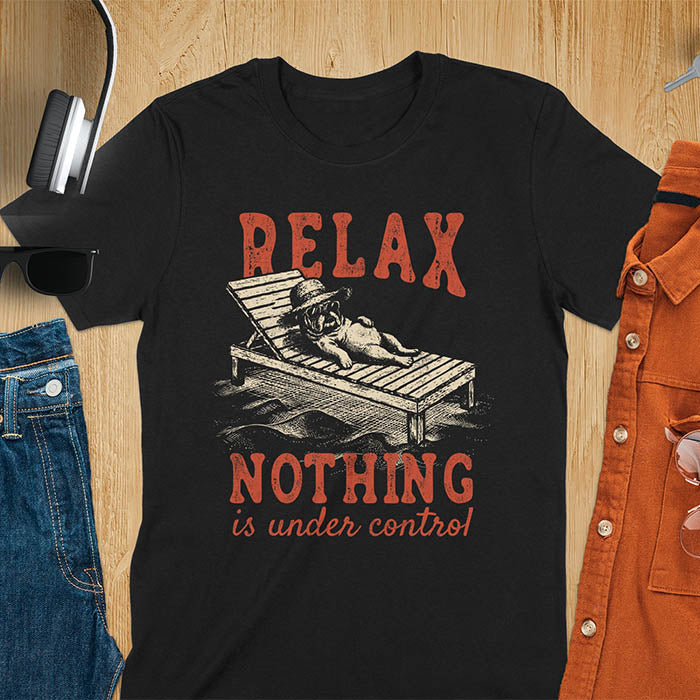 Black t-shirt featuring a bulldog wearing a straw hat lounging on a beach chair with text Relax Nothing Is Under Control in vintage red lettering