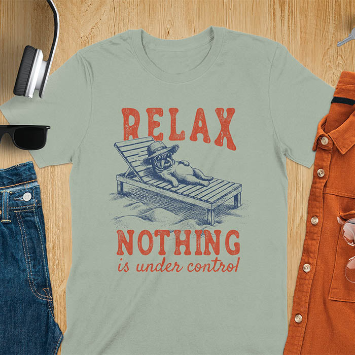 Sage green t-shirt featuring a bulldog wearing a straw hat lounging on a beach chair with text Relax Nothing Is Under Control in vintage red lettering