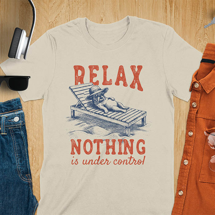 Sand color t-shirt featuring a bulldog wearing a straw hat lounging on a beach chair with text Relax Nothing Is Under Control in vintage red lettering