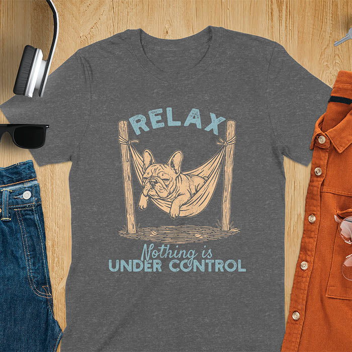 Dark heather t-shirt with vintage-inspired illustration. Retro graphic features French bulldog relaxing in hammock with 'Relax' and 'Nothing is Under Control' text in distressed typography. Quirky zen humor meme design.