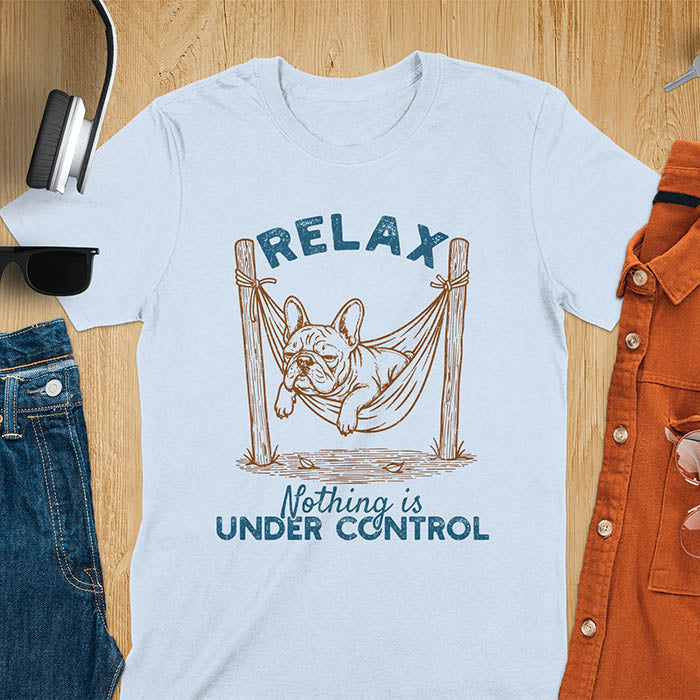 Light blue t-shirt with vintage-inspired illustration. Retro graphic features French bulldog relaxing in hammock with 'Relax' and 'Nothing is Under Control' text in distressed typography. Quirky zen humor meme design.