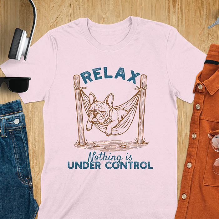 Light pink t-shirt with vintage-inspired illustration. Retro graphic features French bulldog relaxing in hammock with 'Relax' and 'Nothing is Under Control' text in distressed typography. Quirky zen humor meme design.
