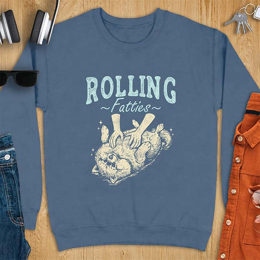 Indigo Blue sweatshirt with a graphic of a fluffy Pomeranian rolled onto its back getting a belly rub from two hands and the text Rolling Fatties