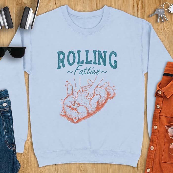 Light Blue sweatshirt with a graphic of a fluffy Pomeranian rolled onto its back getting a belly rub from two hands and the text Rolling Fatties