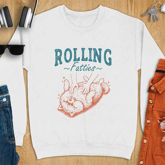 White sweatshirt with a graphic of a fluffy Pomeranian rolled onto its back getting a belly rub from two hands and the text Rolling Fatties
