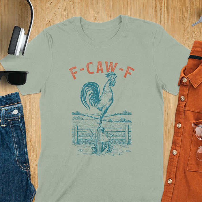 Sage Green t-shirt with F-CAW-F text and detailed rooster illustration standing on wooden fence in vintage farm scene style