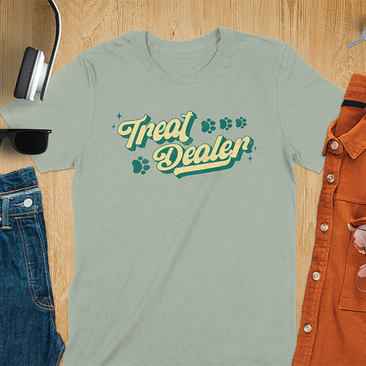 Sage Green t-shirt with Treat Dealer text in retro script typography with green and yellow colors and paw print decorations