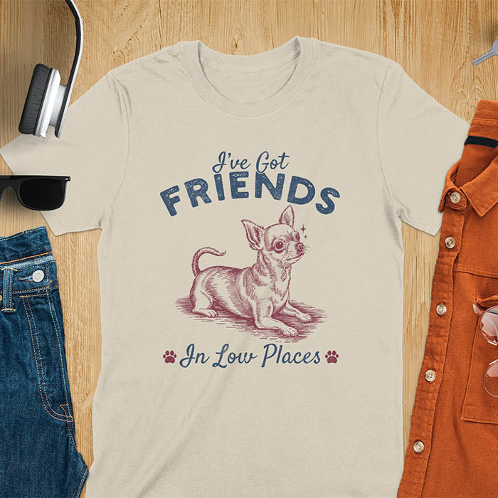 Sand color t-shirt featuring a sitting chihuahua illustration with large ears and paw prints, text reads I've Got Friends In Low Places