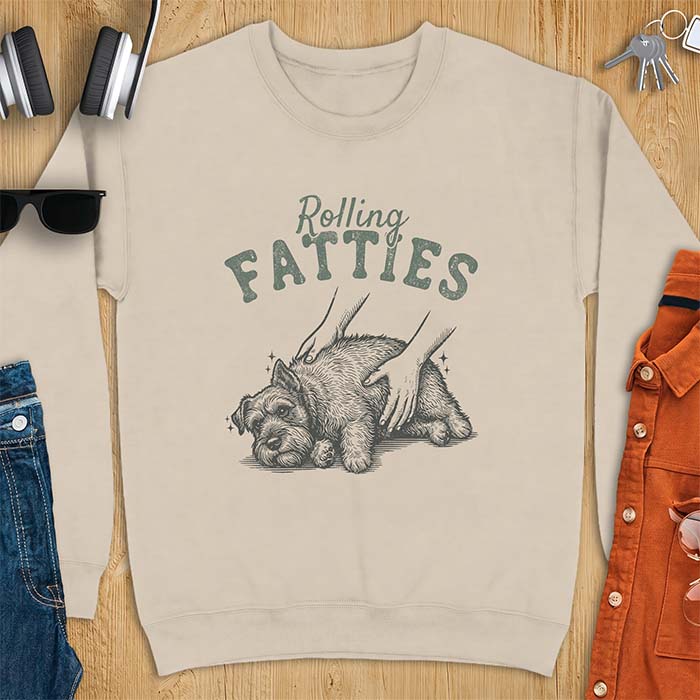 Sand sweatshirt with a graphic of a scruffy Schnauzer lying curled on the ground while two hands reach in to scratch and pet it, plus the text Rolling Fatties above.