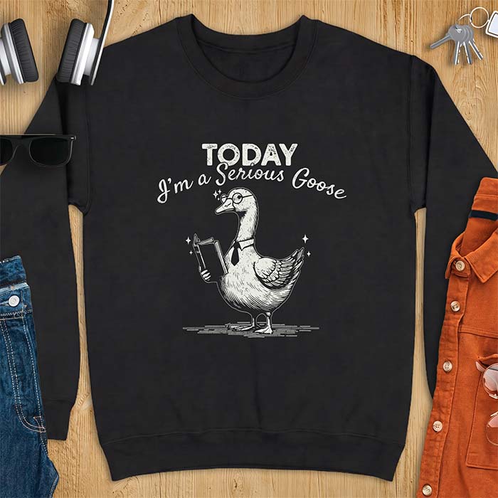 Black sweatshirt with an illustration of a goose wearing round glasses and a necktie, holding an open book, next to sparkle accents and the text Today I'm A Serious Goose.