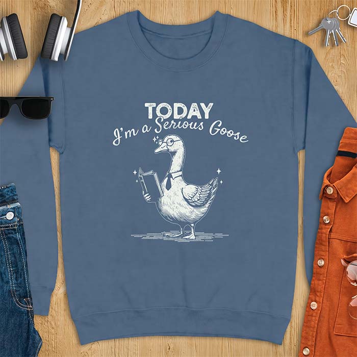 Indigo Blue sweatshirt with an illustration of a goose wearing round glasses and a necktie, holding an open book, next to sparkle accents and the text Today I'm A Serious Goose.