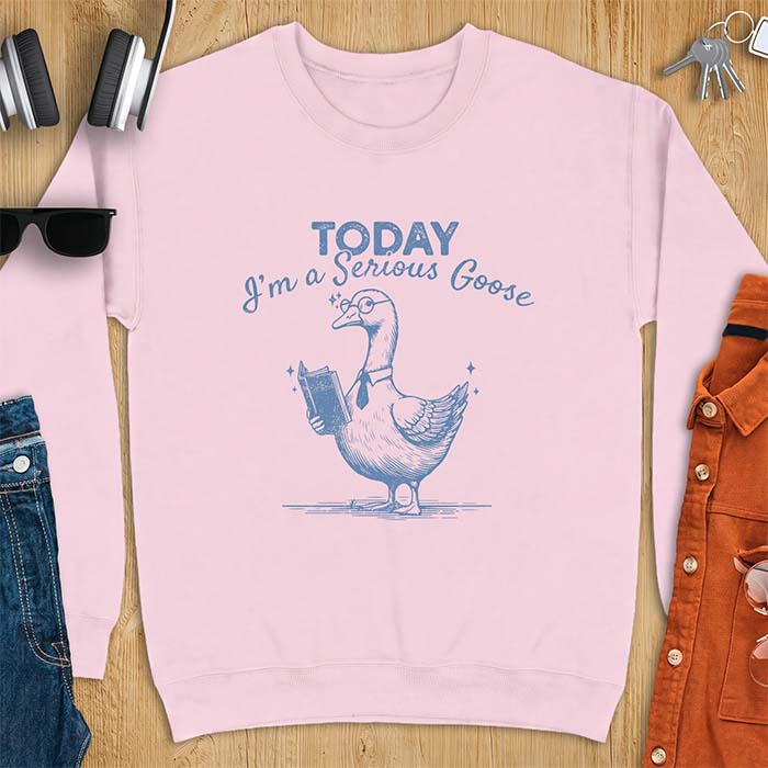 Light Pink sweatshirt with an illustration of a goose wearing round glasses and a necktie, holding an open book, next to sparkle accents and the text Today I'm A Serious Goose.
